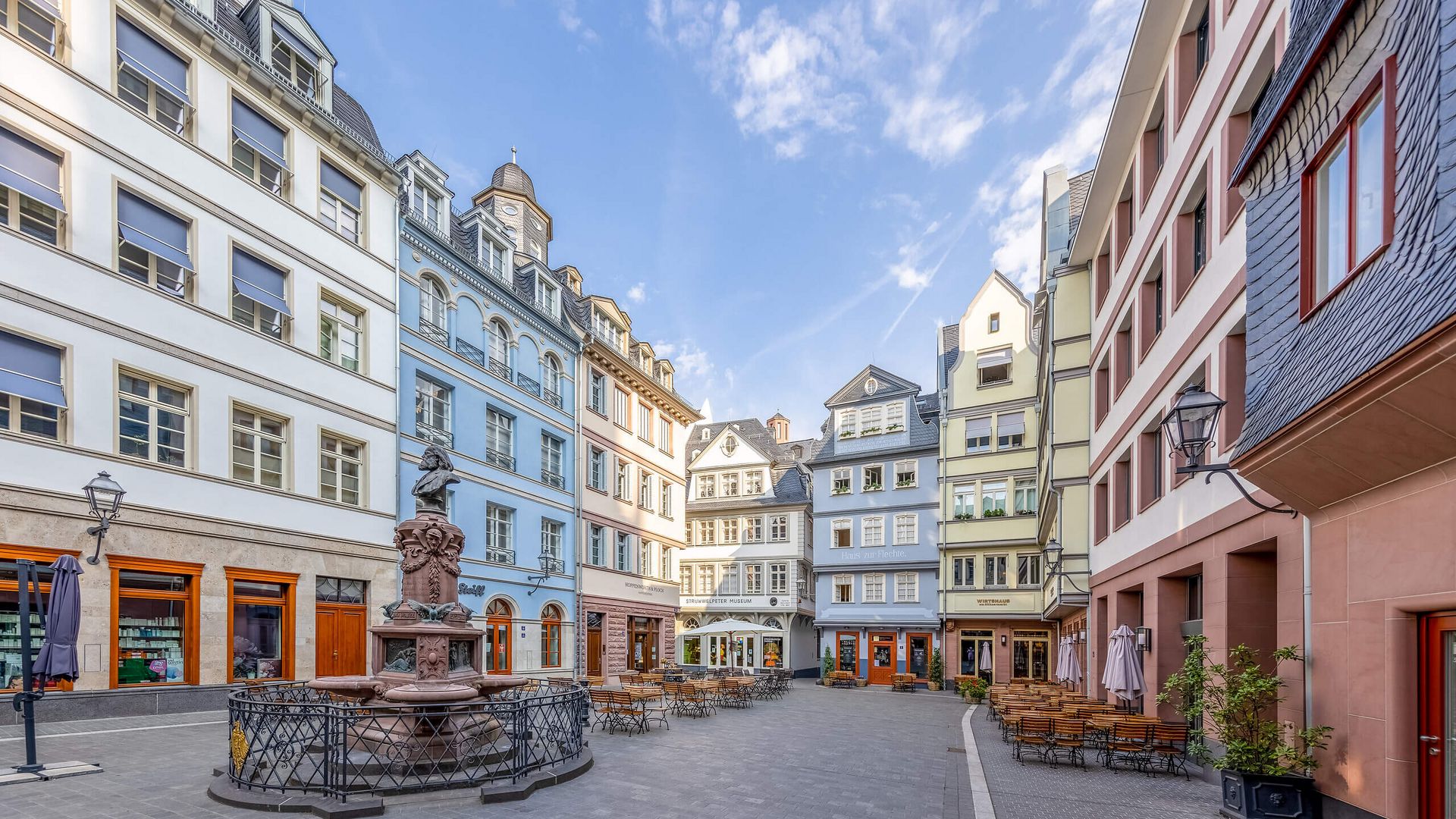 Der Platz Hühnermarkt in der neuen Frankfurter Altstadt mit einem Brunnen und farbenfrohen Gebäuden.