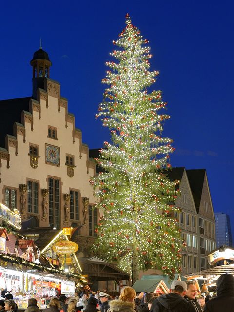 Beleuchteter Weihnachtsbaum auf dem Frankfurter Weihnachtsmarkt 2016 vor der historischen Kulisse des Römers, mit geschmückten Marktständen und vielen Menschen. Das Bild zeigt eine festliche Atmosphäre in der Abenddämmerung.