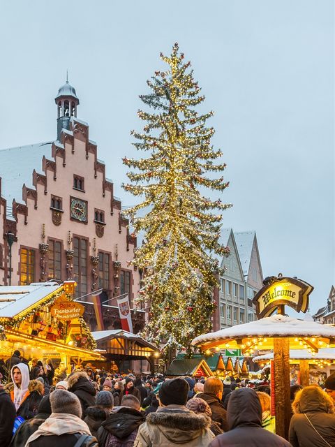 Beleuchteter Weihnachtsbaum auf dem Frankfurter Weihnachtsmarkt 2017 vor der historischen Kulisse des Römers, mit verschneiten Marktständen im Vordergrund. Das Bild zeigt eine festliche Atmosphäre am Tag.