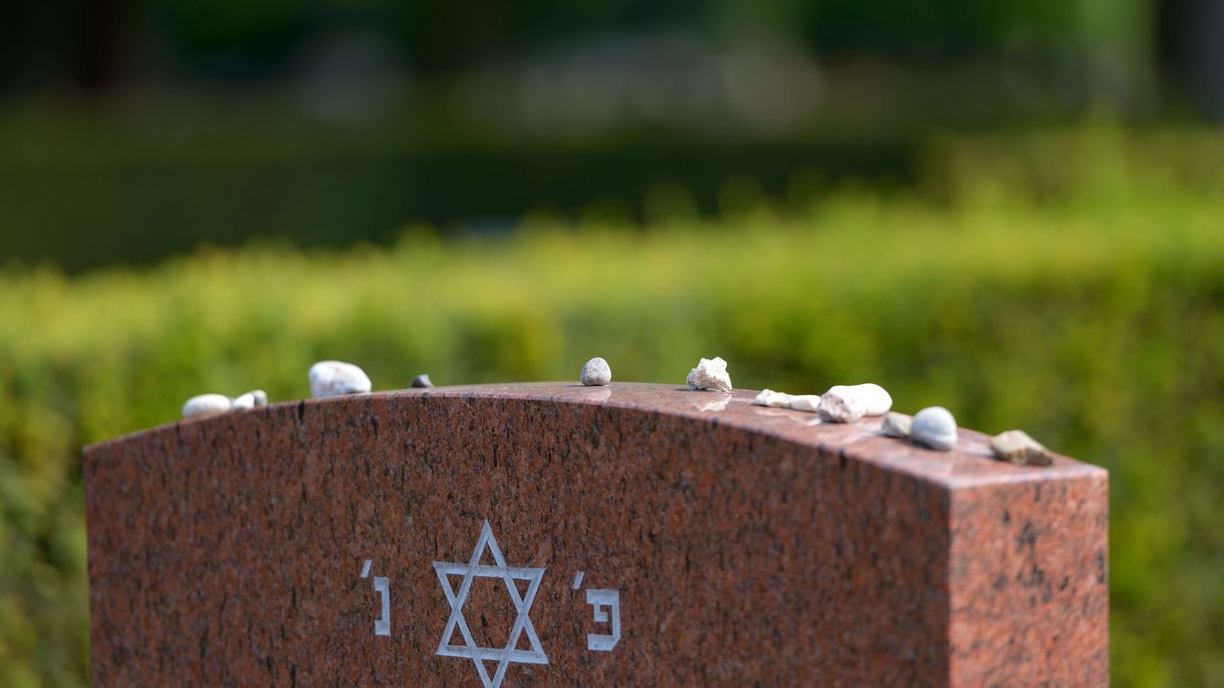 Close-up of a Jewish gravestone with a Star of David and small memorial stones on it.