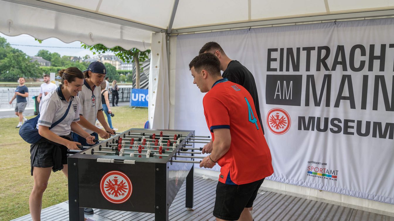 Fans verschiedener Teams spielen an einem Tischkicker im Pop-Up Eintracht Museum gegeneinander. 