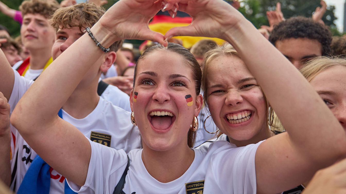Fans der deutschen Nationalmannschaft feiern und jubeln in Deutschland-Trikots. 