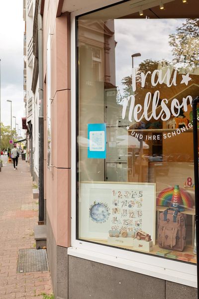 The facade of a shop in Frankfurt's Brückenviertel with a colourful shop window. The surrounding street is characterised by stylish historic buildings.