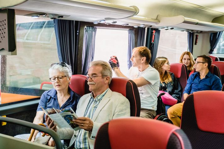 Ein Rollstuhlfahrer und weitere Gäste in einem Bus bei einer Stadtrundfahrt