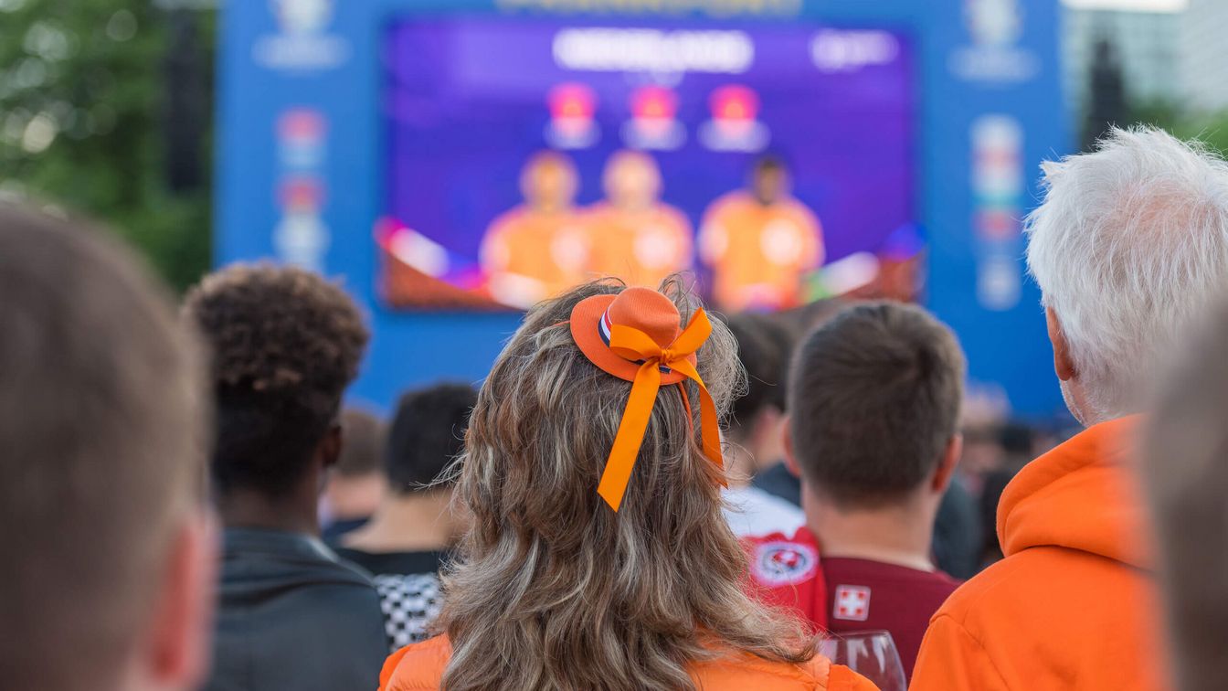 Fans of the Netherlands look at one of the screens on the Fan Zone Mainufer