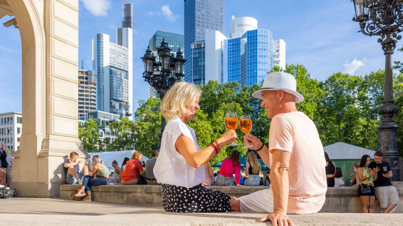 A couple in summery outfits toast each other