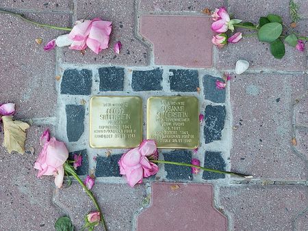 Two Stolpersteine for Georg and Susanne Silberstein, surrounded by flowers, embedded in the pavement.